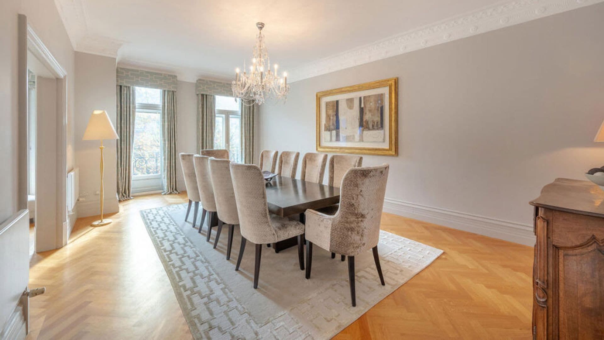 Classic style dining room with a large rectangular table, carpet, spider lamp, pictures and upholstered chairs