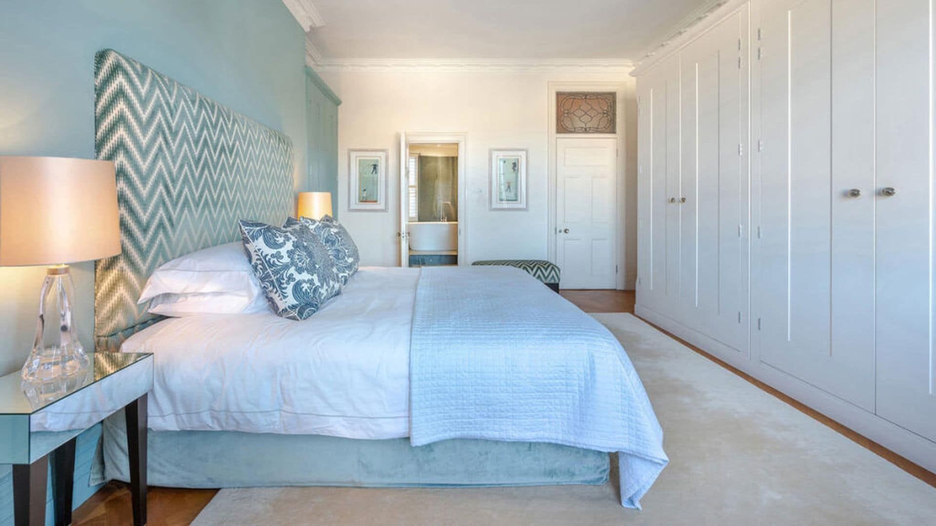 Bedroom with light blue wall, upholstered headboard with geometric design, white cabinet wall, carpet