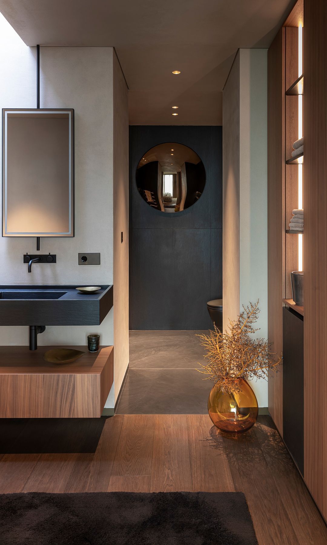 Bathroom with wooden floor walls, black, shelves and mirror round effect