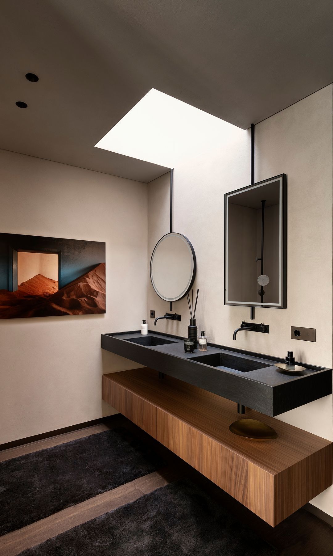 Bathroom with double black sink, wooden furniture, wooden floor, roof window, round mirror and rectangular mirror