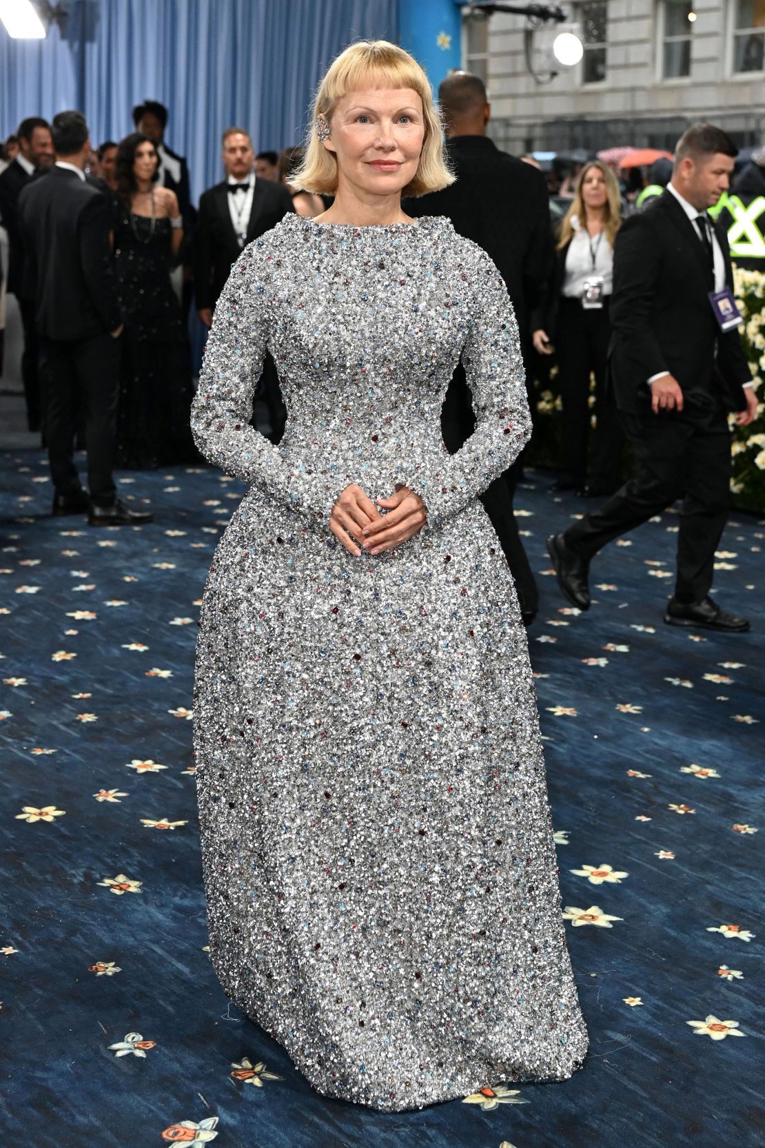 Pamela Anderson, sporting a new bob haircut, arrived in a floor-length, long-sleeved silver sequined gown by Tory Burch.