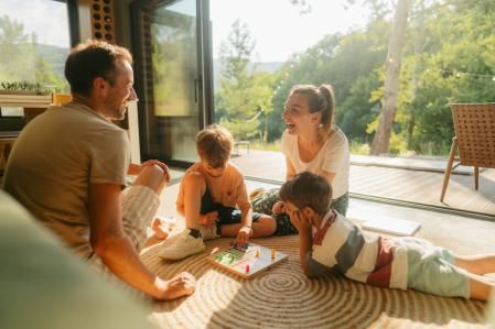 Photo of a young family playing board games together on the floor of their home