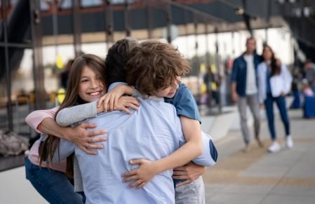 Portrait of two happy kids greeting their father at the airport after coming home from a trip – lifestyle concepts
