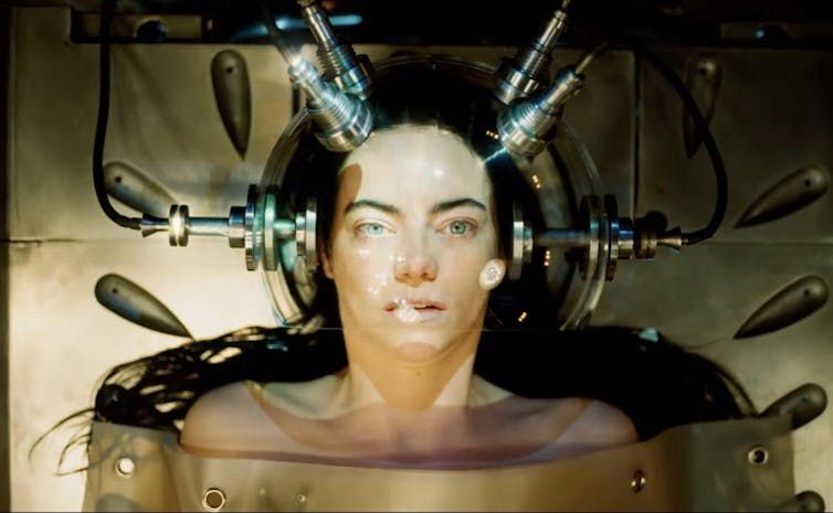 A woman lying with many devices pointing to her head.
